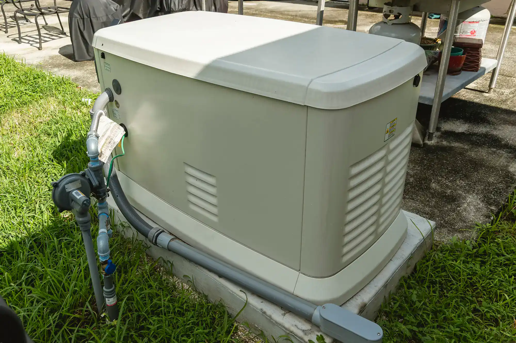 A standby home generator sits on a concrete pad outside in RI, surrounded by grass, with electrical and gas connections professionally installed by electricians Rhode Island trusts.